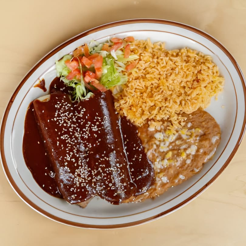 Si Amigos' enchiladas with rich mole sauce, sesame seeds, rice, refried beans, and fresh salad.