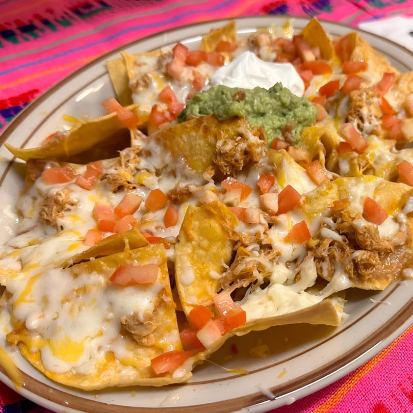 Si Amigos' chicken nachos with melted cheese, diced tomatoes, guacamole, and sour cream.